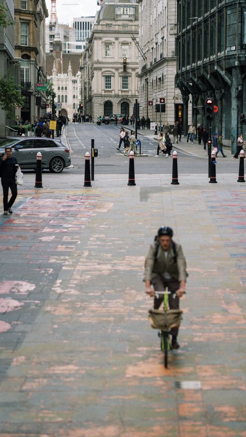 Free A cyclist rides through a busy urban street, capturing the essence of European city life. Stock Photo