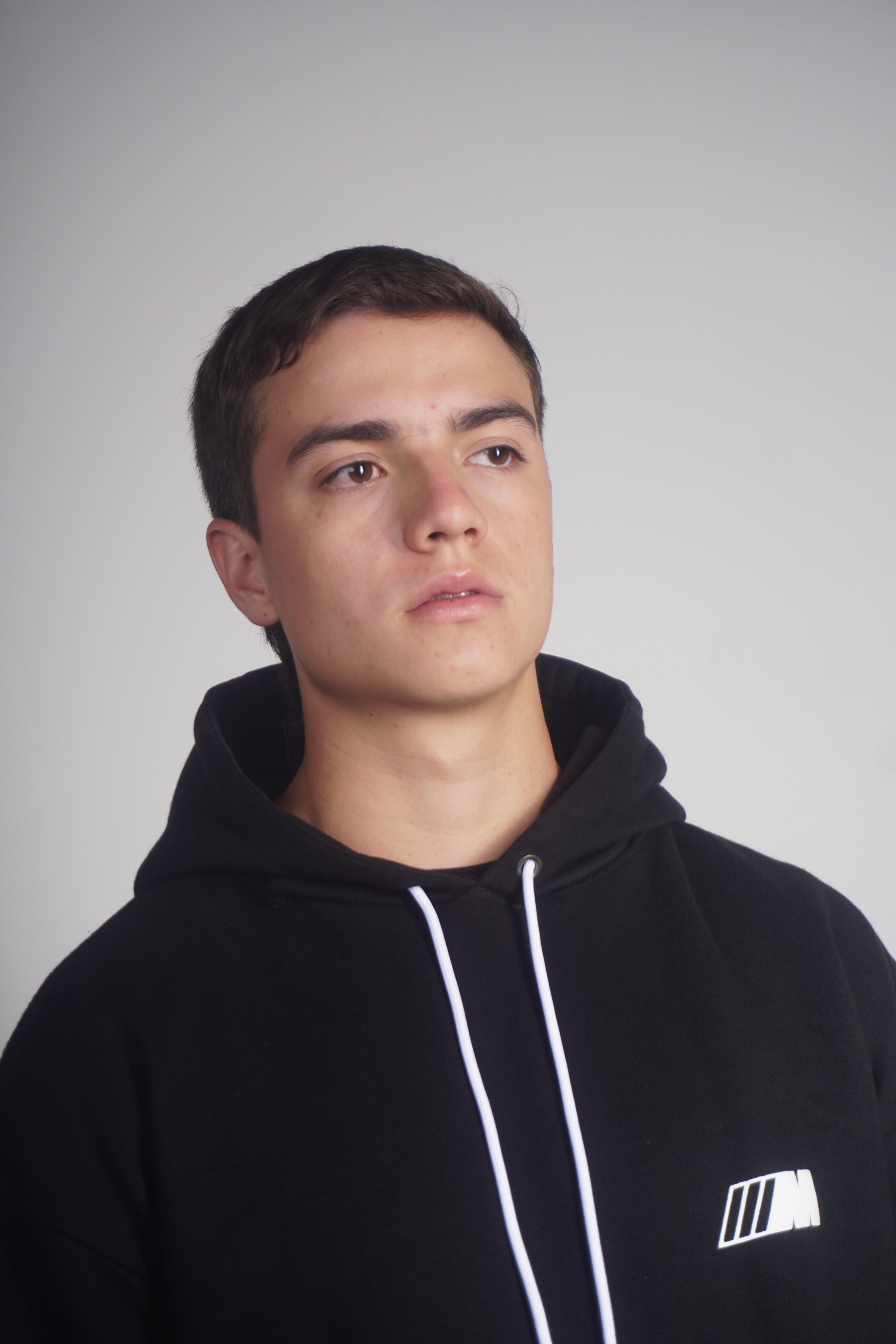 Portrait of a young adult wearing a black hoodie, looking thoughtful.