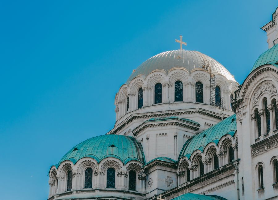 The iconic domes of Alexander Nevsky Cathedral against a clear blue sky in Sofia, Bulgaria.