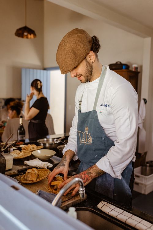 Free A chef wearing a cap and apron cooking in a warm, inviting kitchen environment. Stock Photo