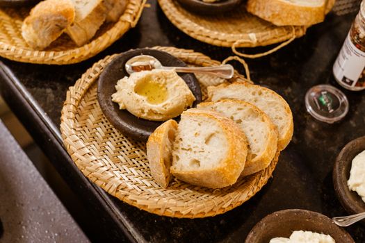 Artisan bread slices with hummus and olive oil on a woven plate for a rustic dining experience.