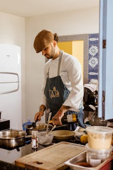 A chef in a white uniform and apron cooks in a contemporary kitchen.