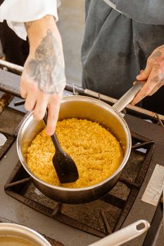 Chef skillfully stirs creamy risotto in a pan on a gas stove, showcasing culinary art.