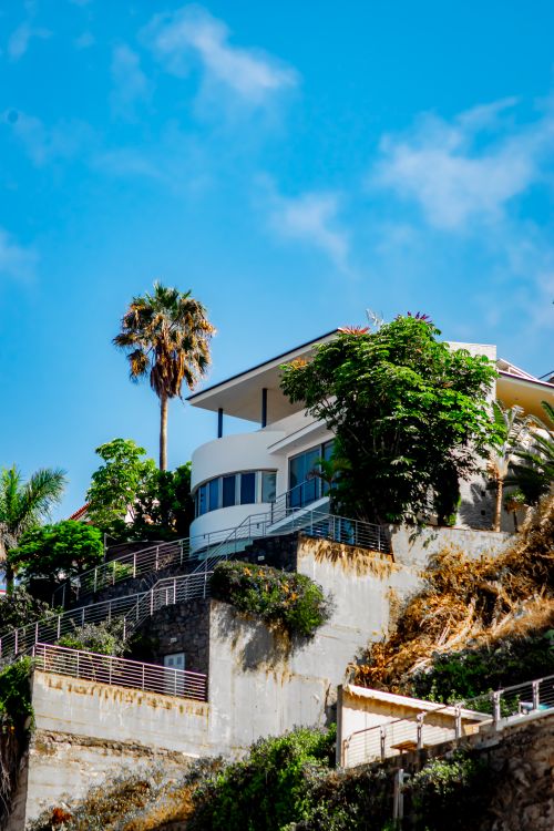 Free Elegant villa on a Spanish hillside surrounded by palm trees and lush greenery. Stock Photo