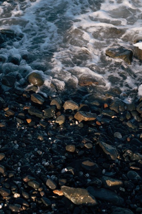 Free Ocean waves gently wash over a rocky shoreline, creating a calming scene. Stock Photo