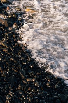 Captivating view of pebbles on a beach with ocean waves at sunrise.