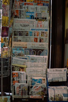 A Paris newsstand displaying international newspapers, reflecting diverse media in a French setting.