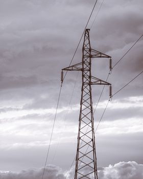 Electricity pylon with power lines against a dramatic cloudy sky in Tunisia.