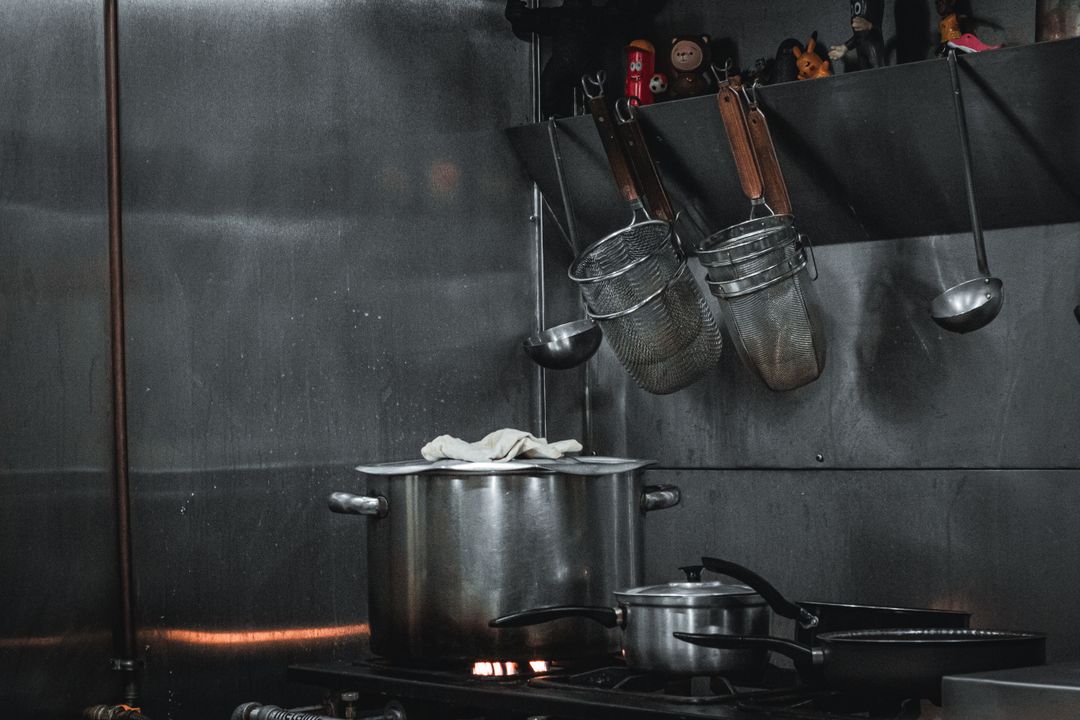 Banquet Chef Career Path: The Large-Scale Cooking Skills Hotels Look For 2 A stainless steel commercial kitchen of the kind a banquet chef career is built in, with bulk pots, strainers and utensils on a rail