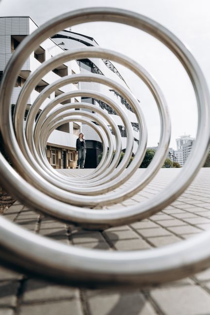 Artistic geometric spiral sculpture outdoors in urban setting with person in background.