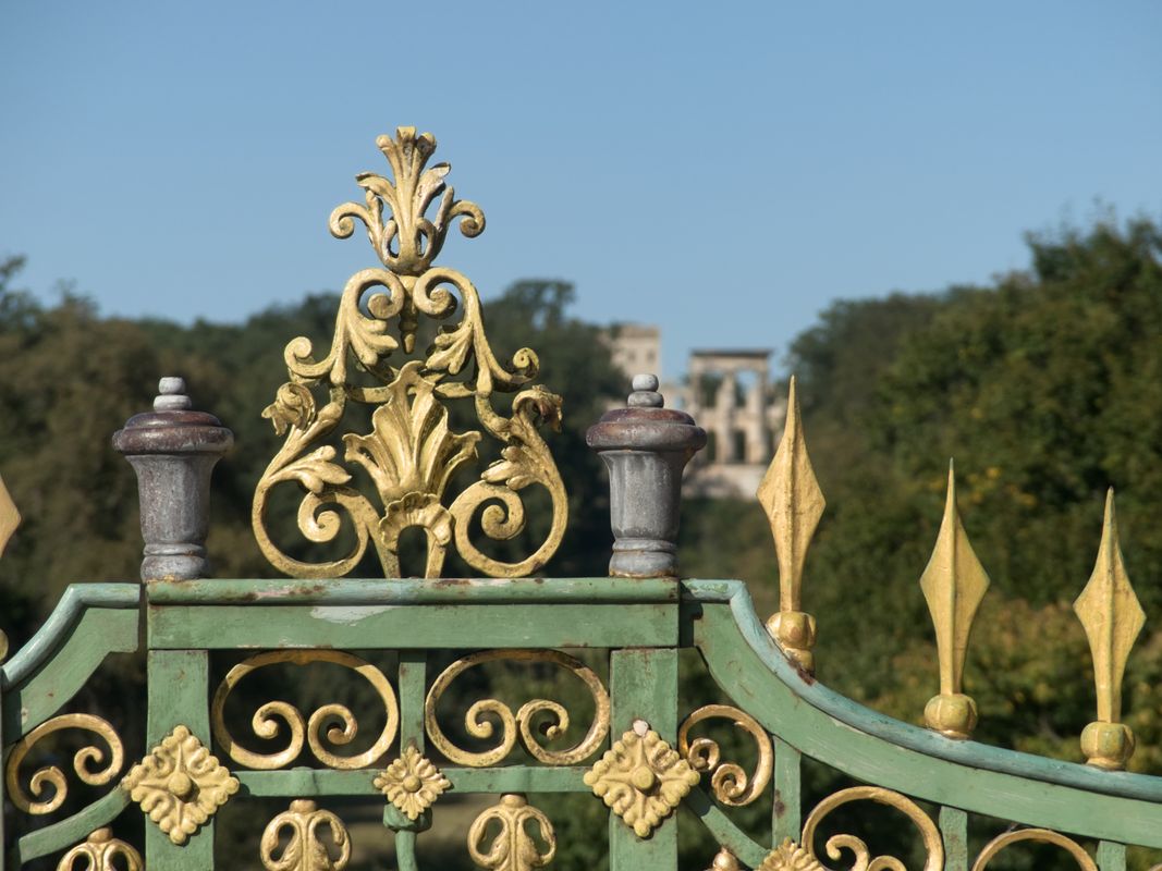 An ornate iron gate standing open against the sky - Give Thanks