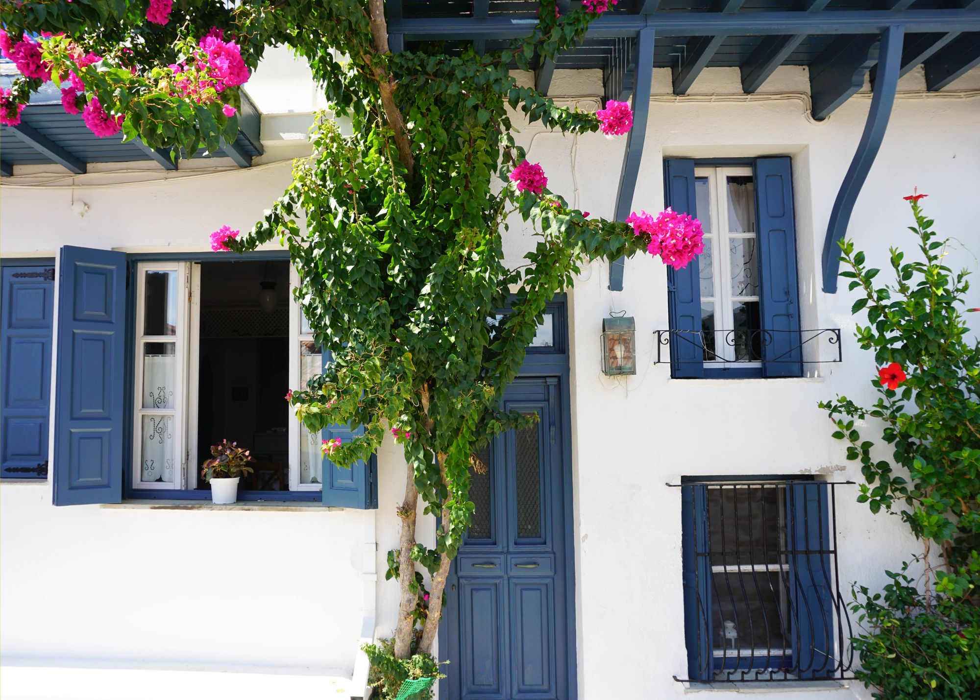 Whitewashed island house with blue shutters and pink bougainvillea, Paros