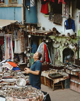 A man explores a vibrant street filled with traditional market stalls and textiles.