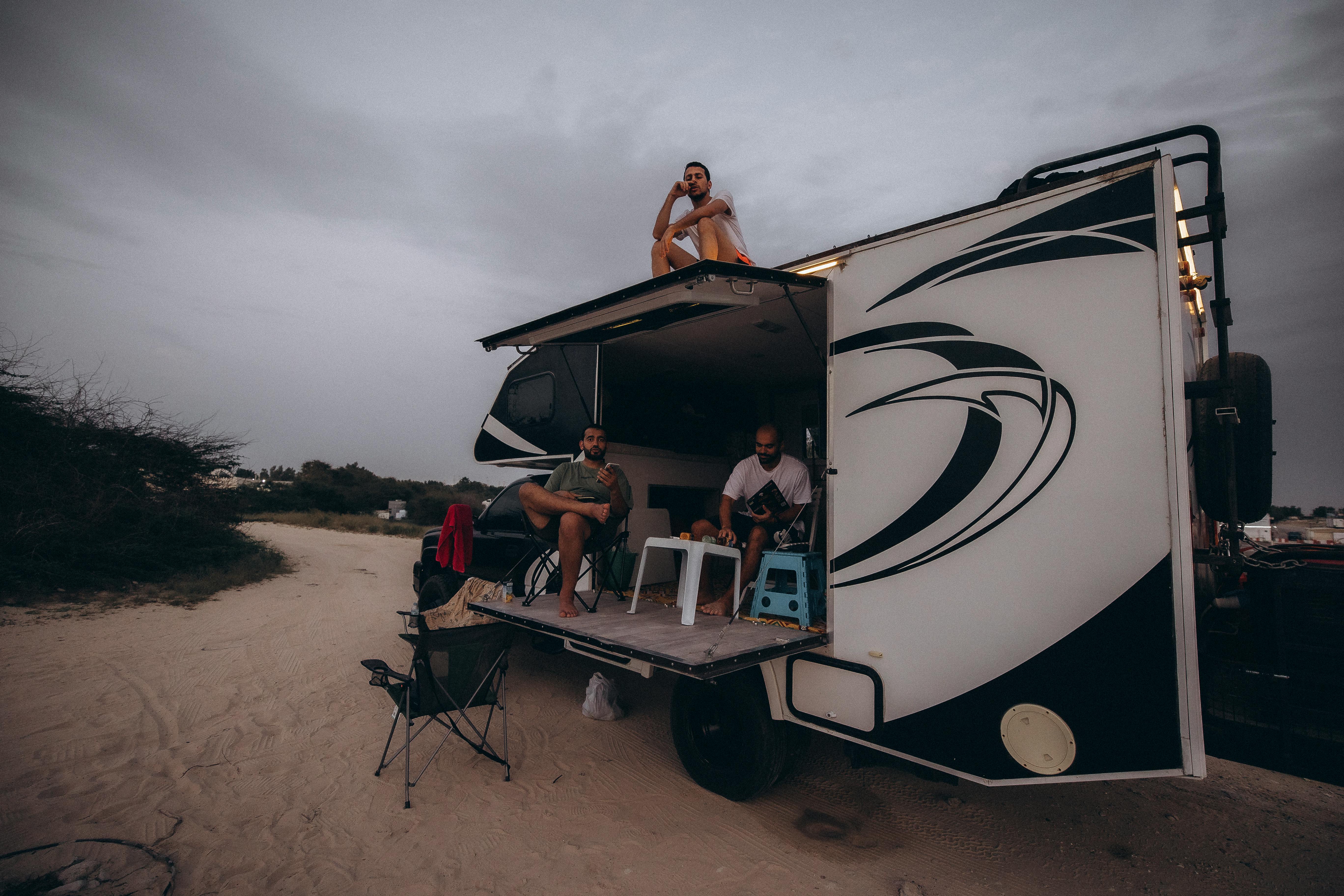 Free People enjoying a camping trip with a truck in Dubai's desert under a cloudy sky. Stock Photo