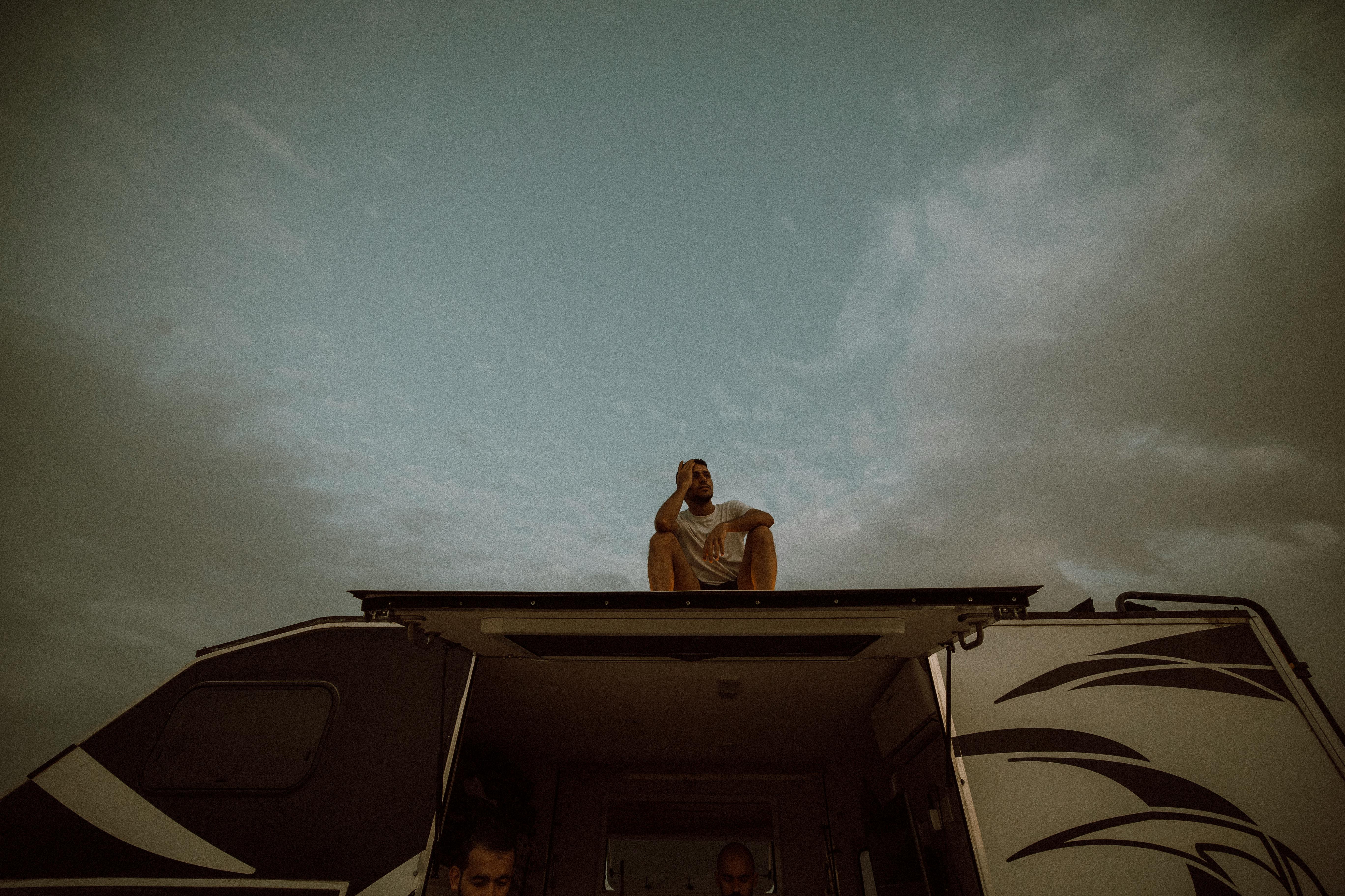 Free A man enjoys the scenic view from the rooftop of an RV under a dramatic cloudy sky in Dubai, UAE. Stock Photo