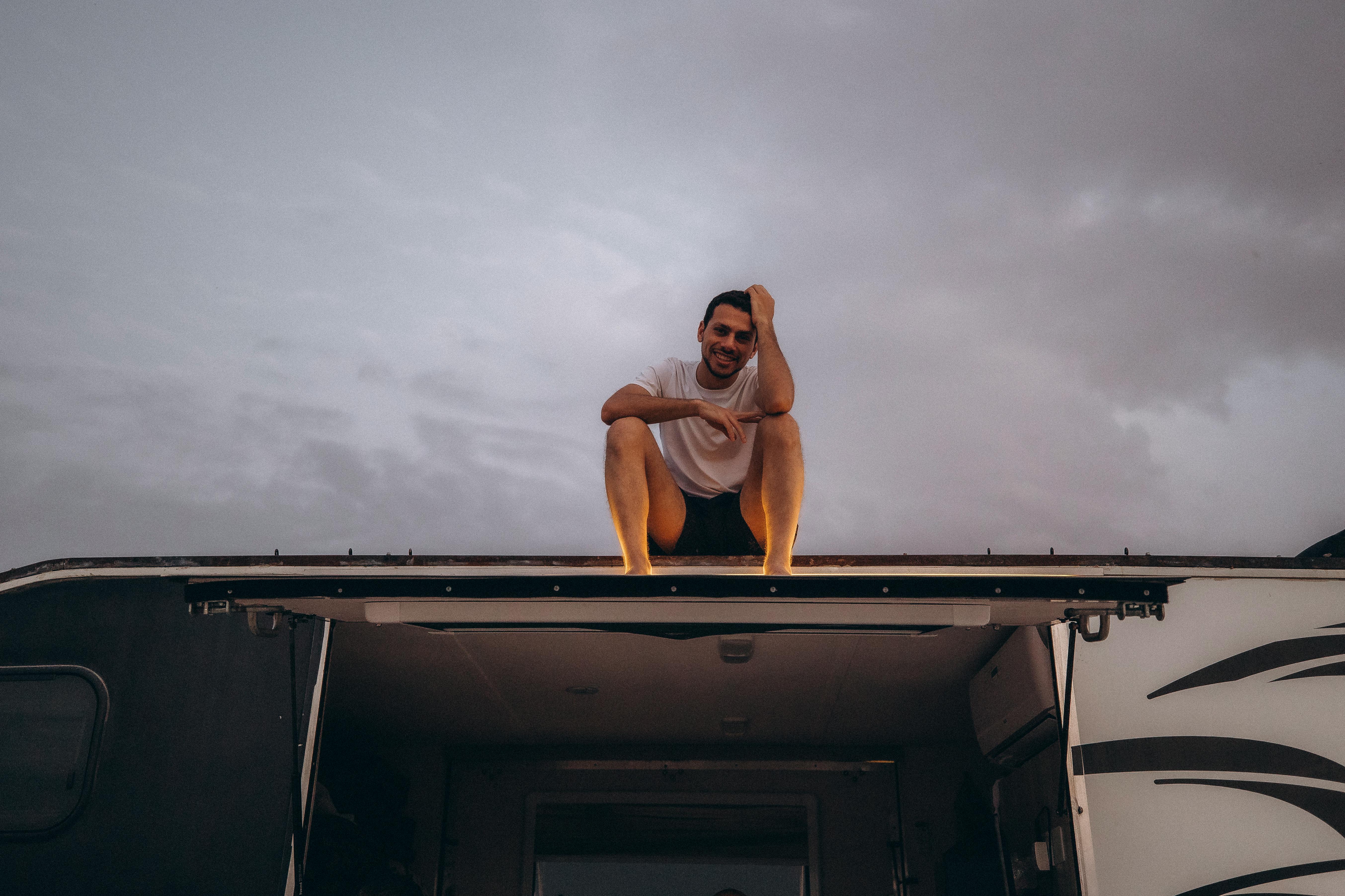 Free A man sits on top of a camper enjoying a cloudy day in Dubai. Perfect for travel and lifestyle themes. Stock Photo