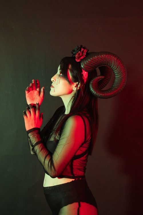 Free A mysterious woman in fantasy attire with horns under dramatic lighting. Stock Photo
