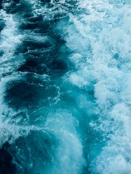 Close-up of a turquoise ocean wave showing dynamic, foamy motion.