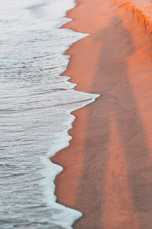 Free Serene view of waves caressing the sandy shore at Tabarka Beach, Tunisia during sunset. Stock Photo