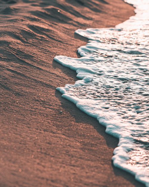 Free Peaceful sunset waves touch the sandy shore of Tabarka Beach, offering a serene coastal escape. Stock Photo