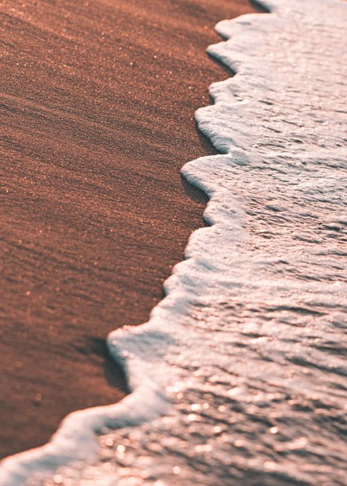 Free Calm waves gently caressing the sandy shore during sunset in Tabarka, Tunisia. Stock Photo