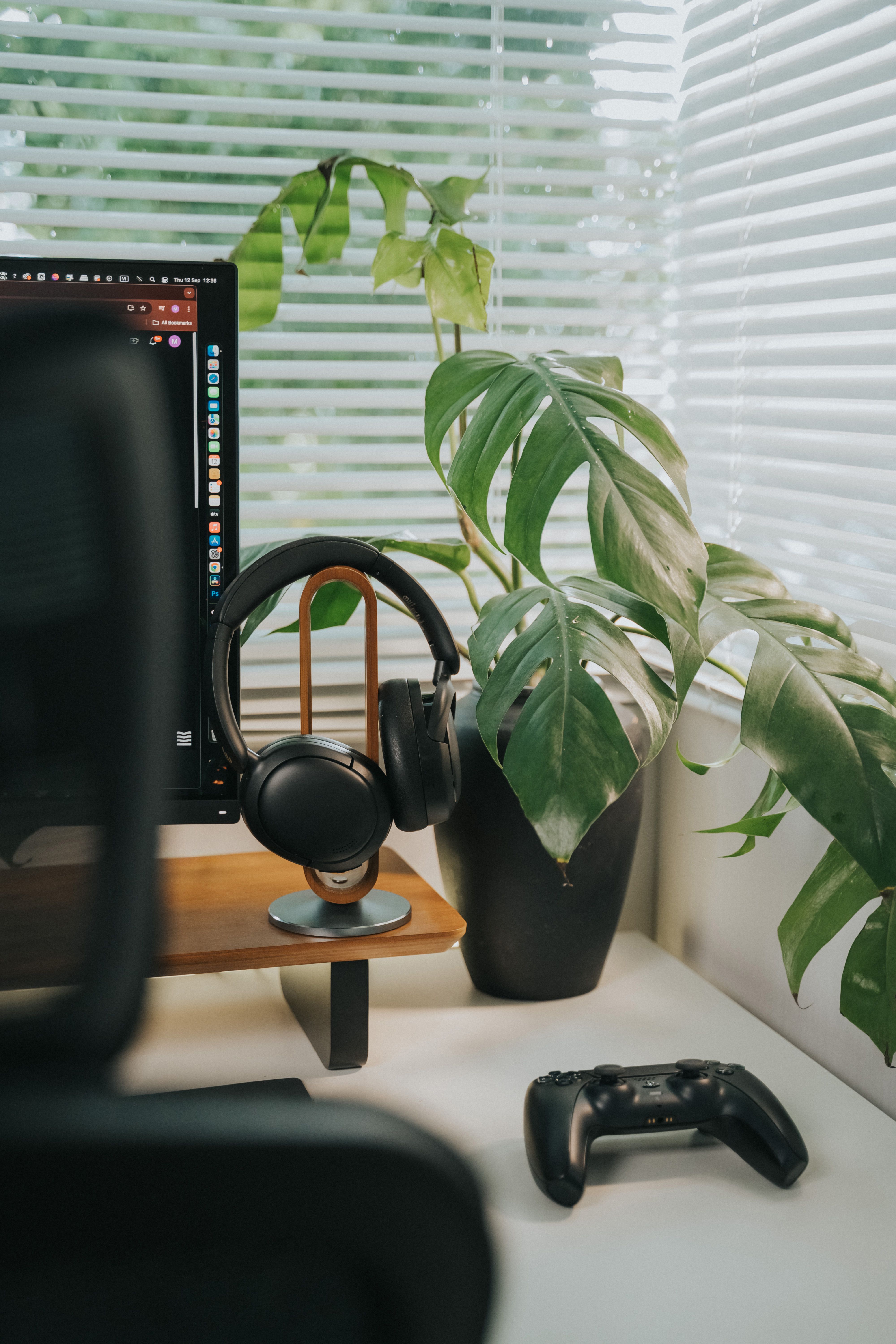 Sleek workspace featuring headphones, game controller, and indoor plant for a modern vibe.