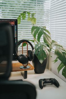Sleek workspace featuring headphones, game controller, and indoor plant for a modern vibe.