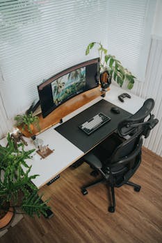 Stylish home office setup featuring a curved monitor and houseplants for a fresh workspace.