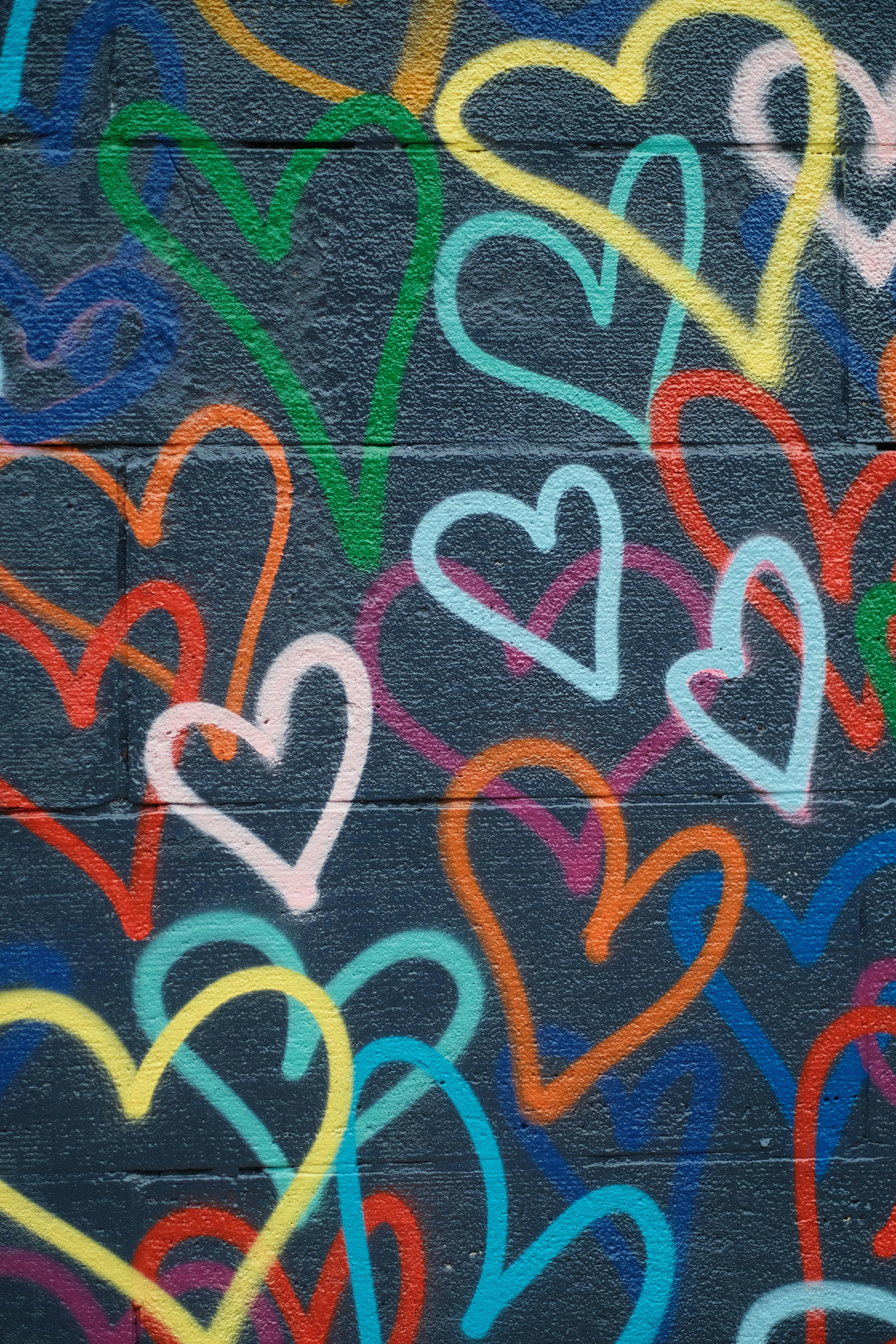 Vibrant graffiti art featuring colorful heart patterns on a concrete wall.