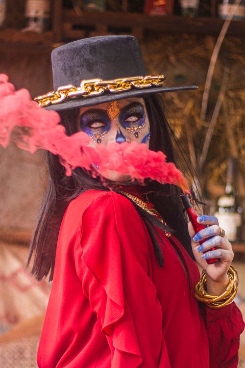 Free Woman with intricate Day of the Dead makeup holding a red smoke bomb. Stock Photo
