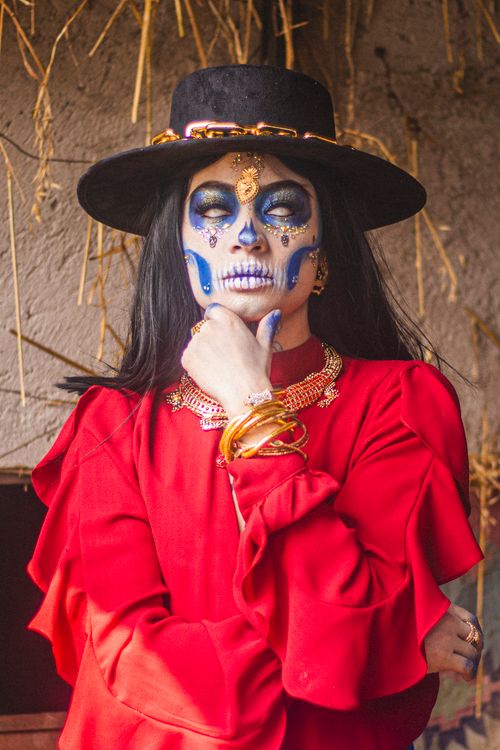 Free Vibrant Day of the Dead makeup on a woman in a red dress and hat. Stock Photo