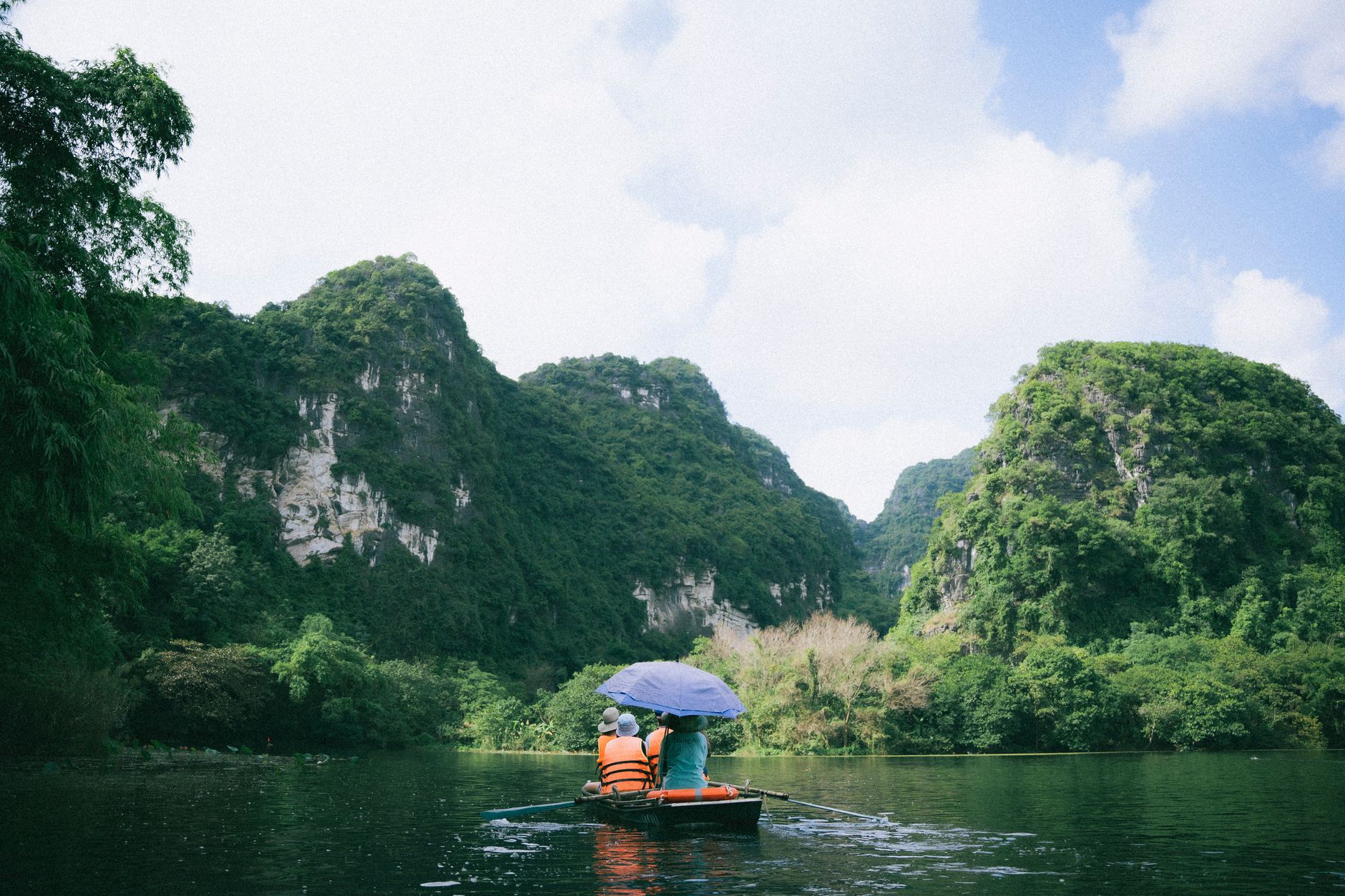 Scenic boat journey in Ninh Bình, Vietnam, surrounded by lush limestone mountains.
