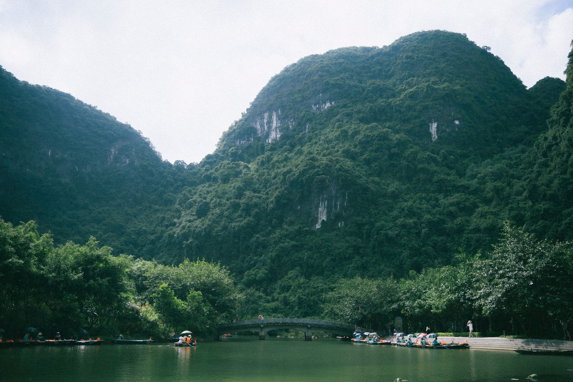 Peaceful landscape of lush limestone mountains and tranquil river in Ninh Bình, Vietnam.