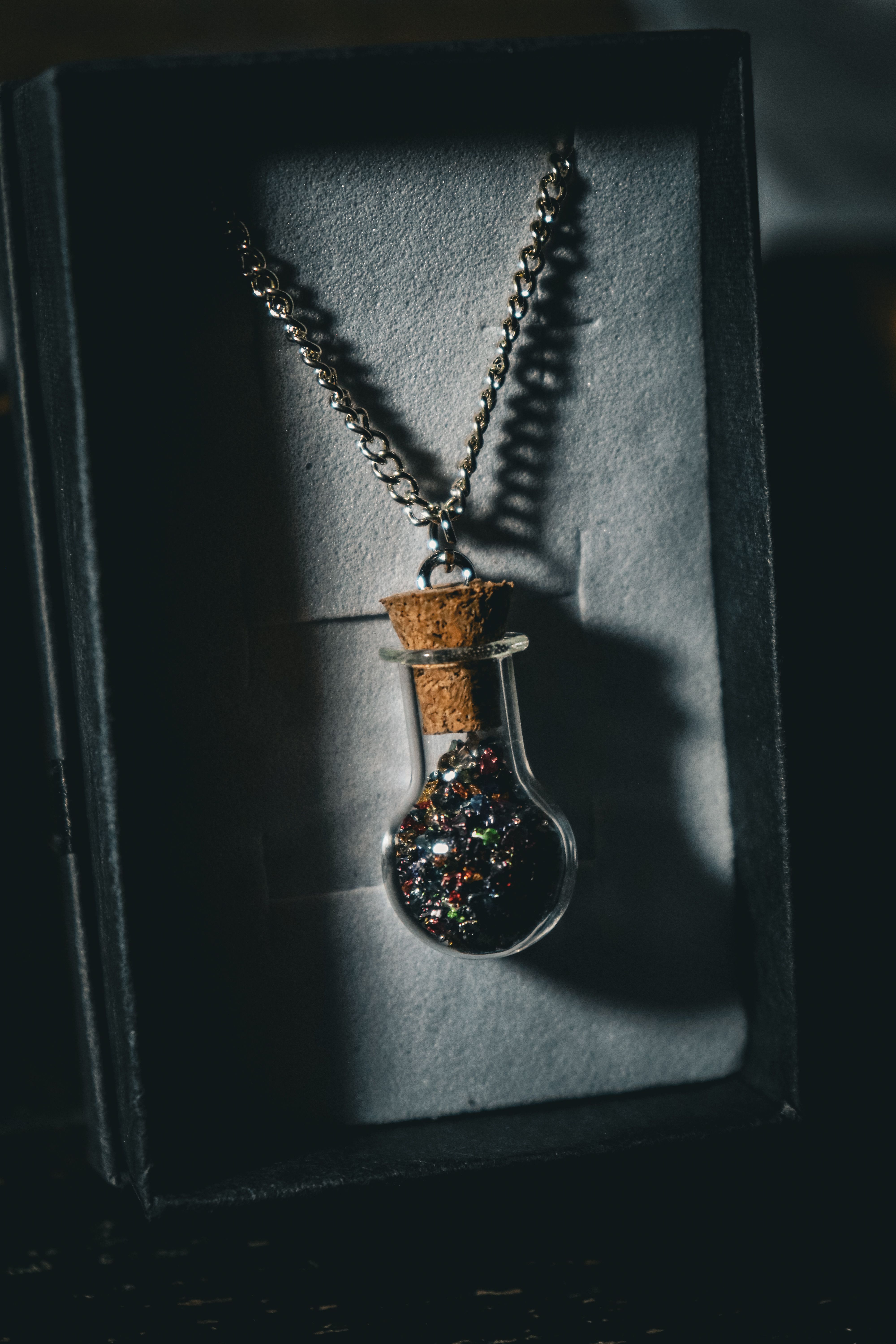 Stylish necklace featuring a glass bottle pendant filled with glitter, presented in a gift box.