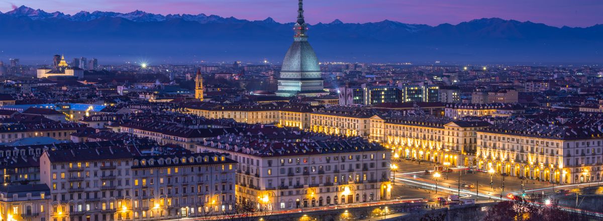 Stunning nighttime view of Turin's cityscape featuring the iconic Mole Antonelliana against a vibrant twilight sky.