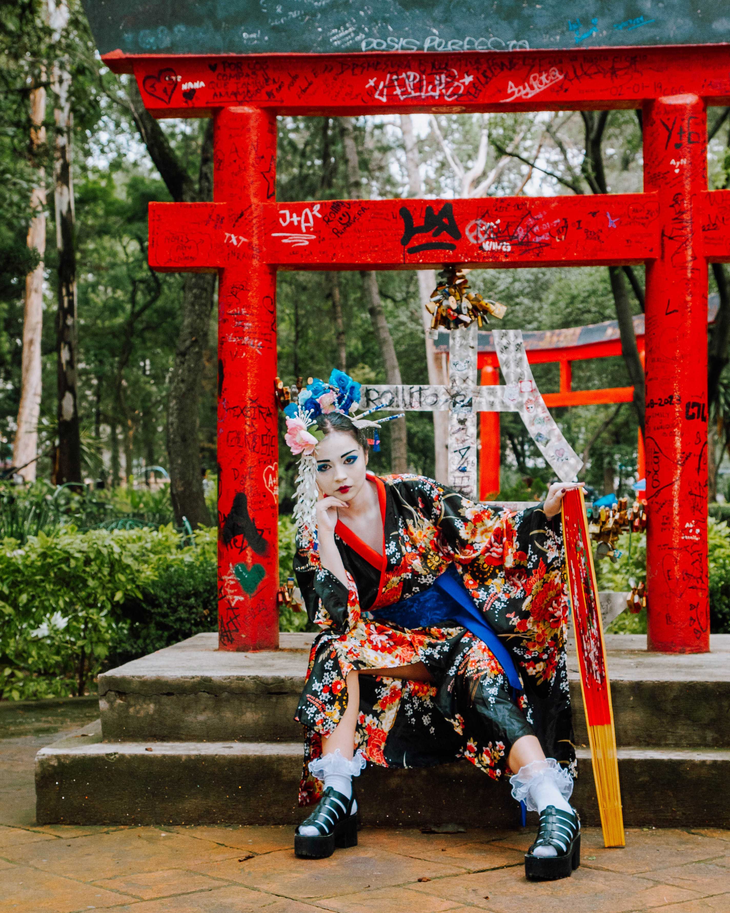 A contemporary geisha in a traditional kimono poses against a graffiti-covered torii gate, blending tradition with urban art.
