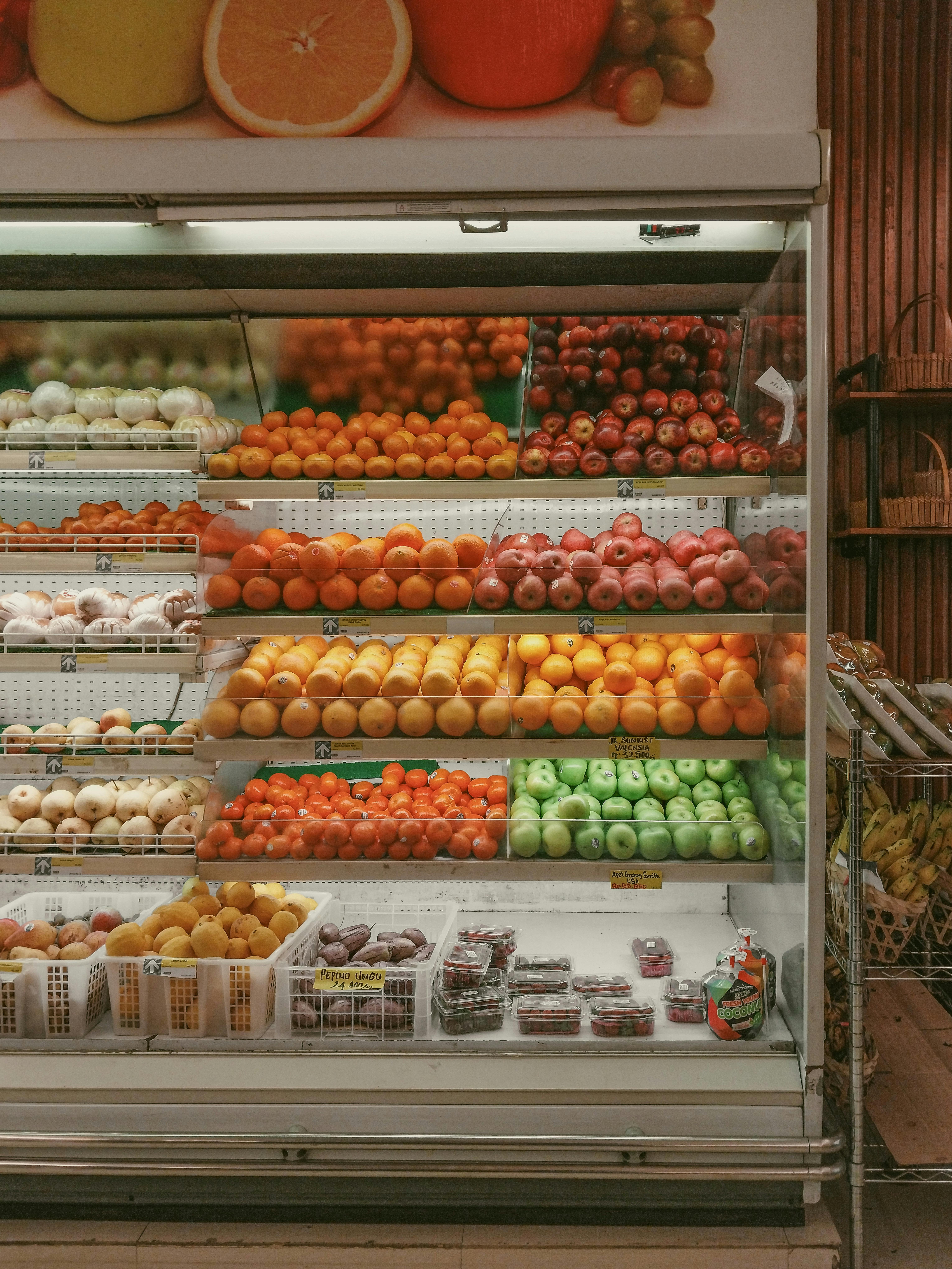 A vibrant selection of fresh fruits neatly arranged in a supermarket refrigerated display.