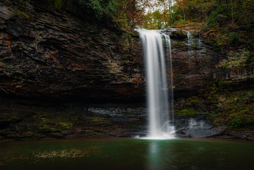 A tranquil waterfall cascading over rugged cliffs surrounded by lush greenery, creating a serene nature scene.