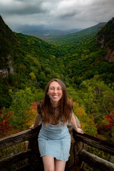 A young woman smiling while enjoying a breathtaking view of lush green mountains.