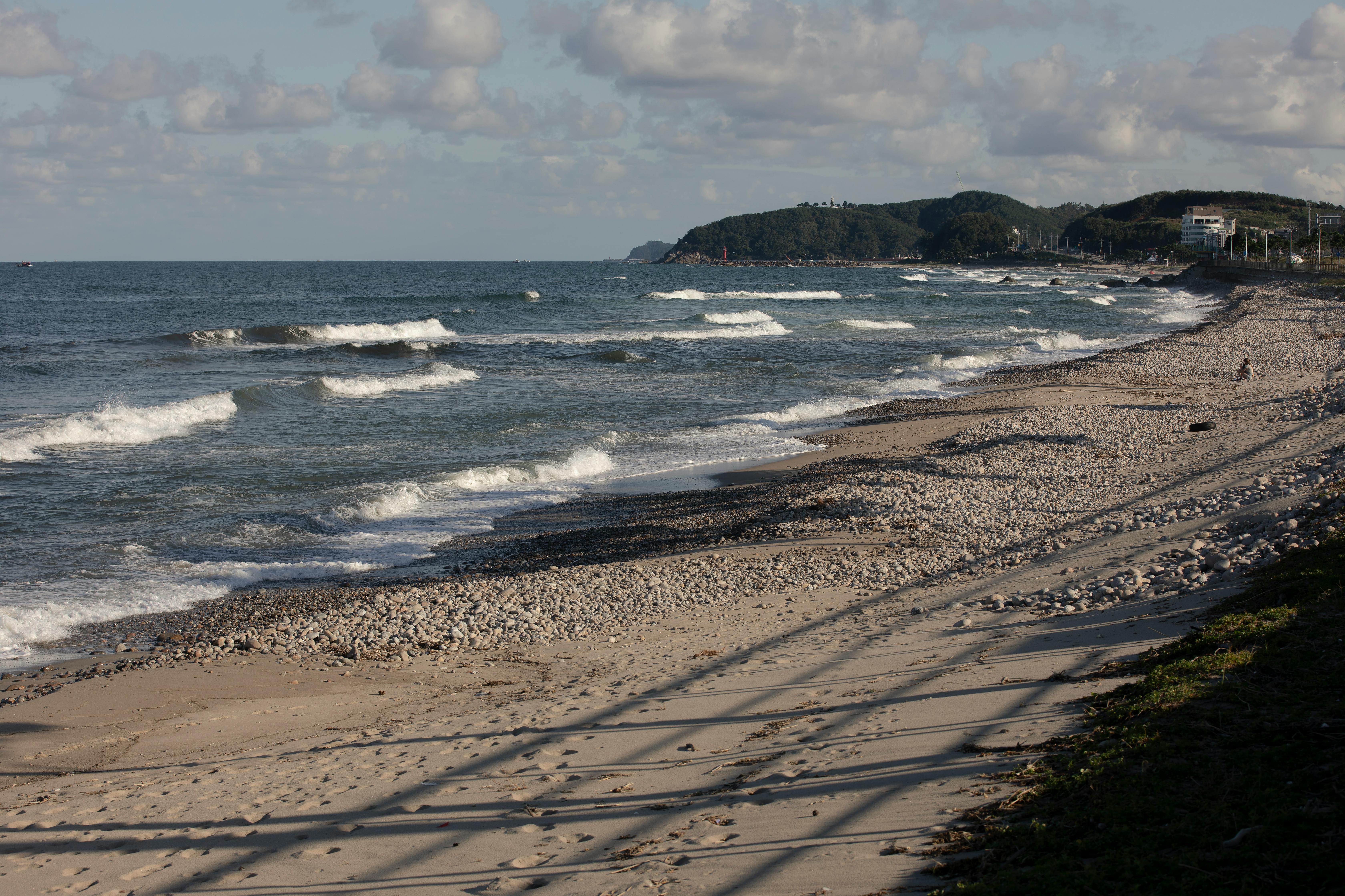 Peaceful rocky beach with gentle waves and a scenic horizon at sunset.