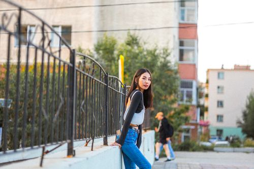 Free Stylish young woman leaning against a fence in a lively urban setting. Stock Photo