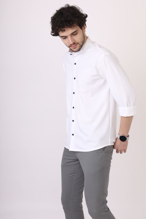 Free Young man in a stylish white shirt standing in a studio setting with a watch on his wrist. Stock Photo