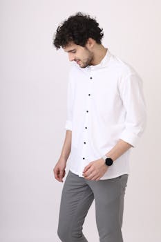 Man wearing white shirt and gray pants, looking down, isolated on white background.