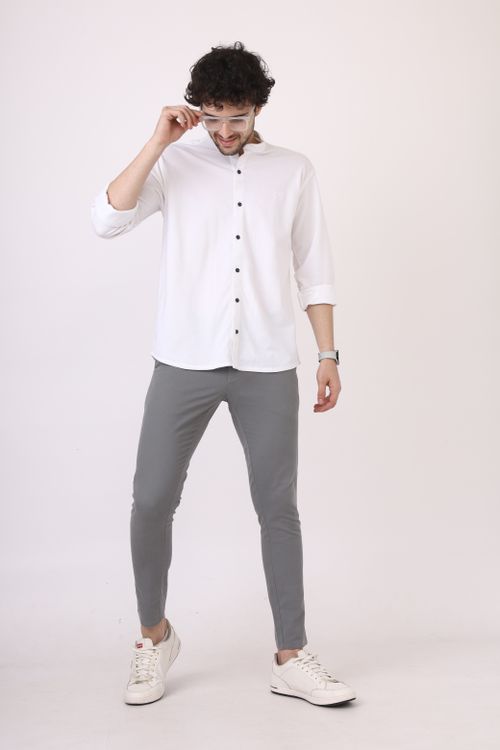 Free Man wearing white shirt and grey pants stands confidently indoors. Stock Photo