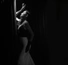 一位时尚的女性以深色背景和黑白窗帘引人注目地摆姿势