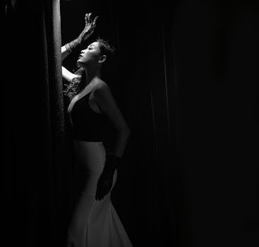 一位时尚女性在黑色背景和黑白窗帘前戏剧性地摆出姿势