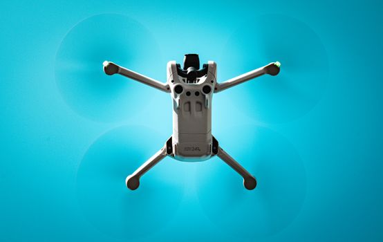 Aerial view of a drone flying against a vibrant blue sky, showcasing modern technology.