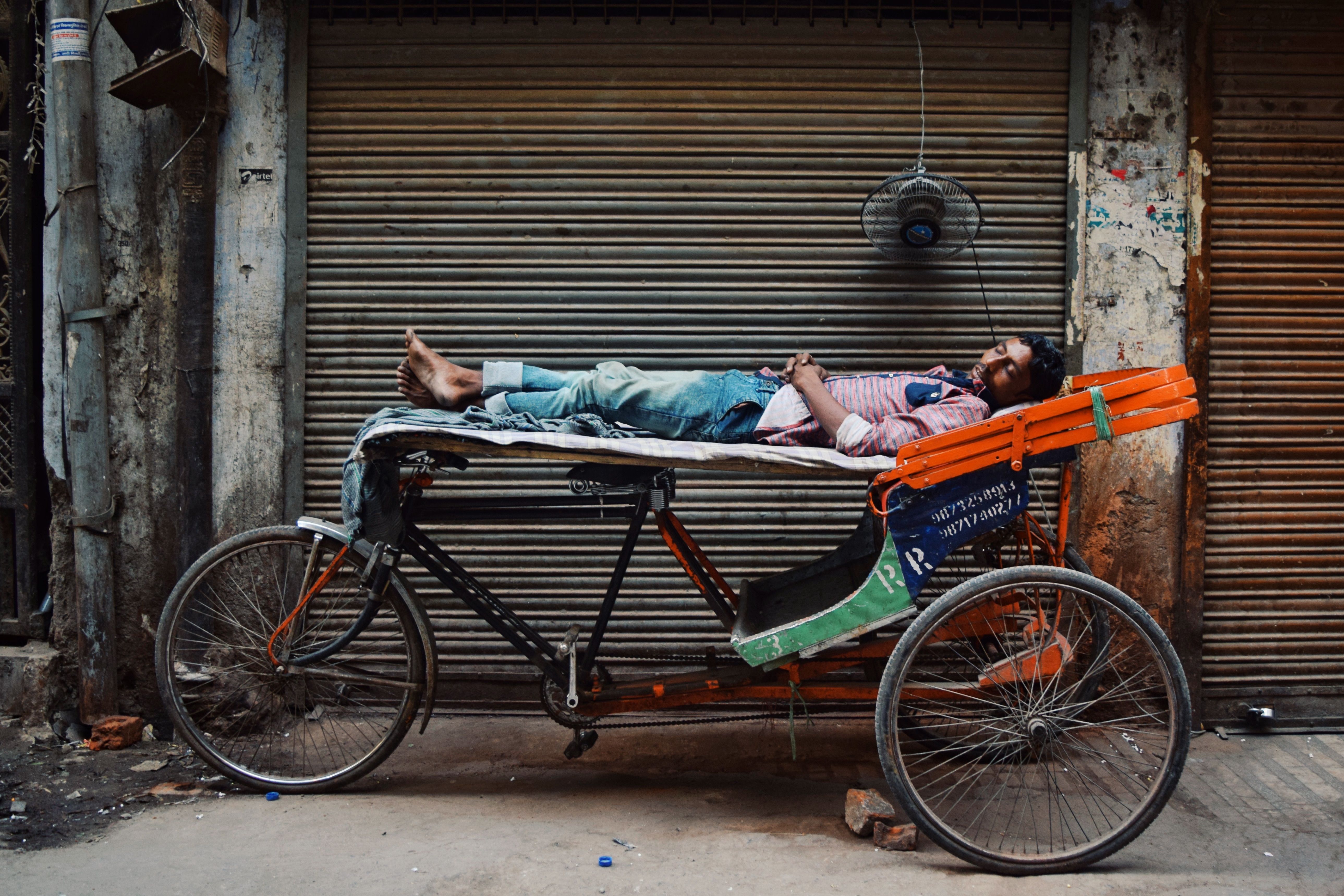 Man Resting on Rickshaw in Urban Street Scene · Free Stock Photo