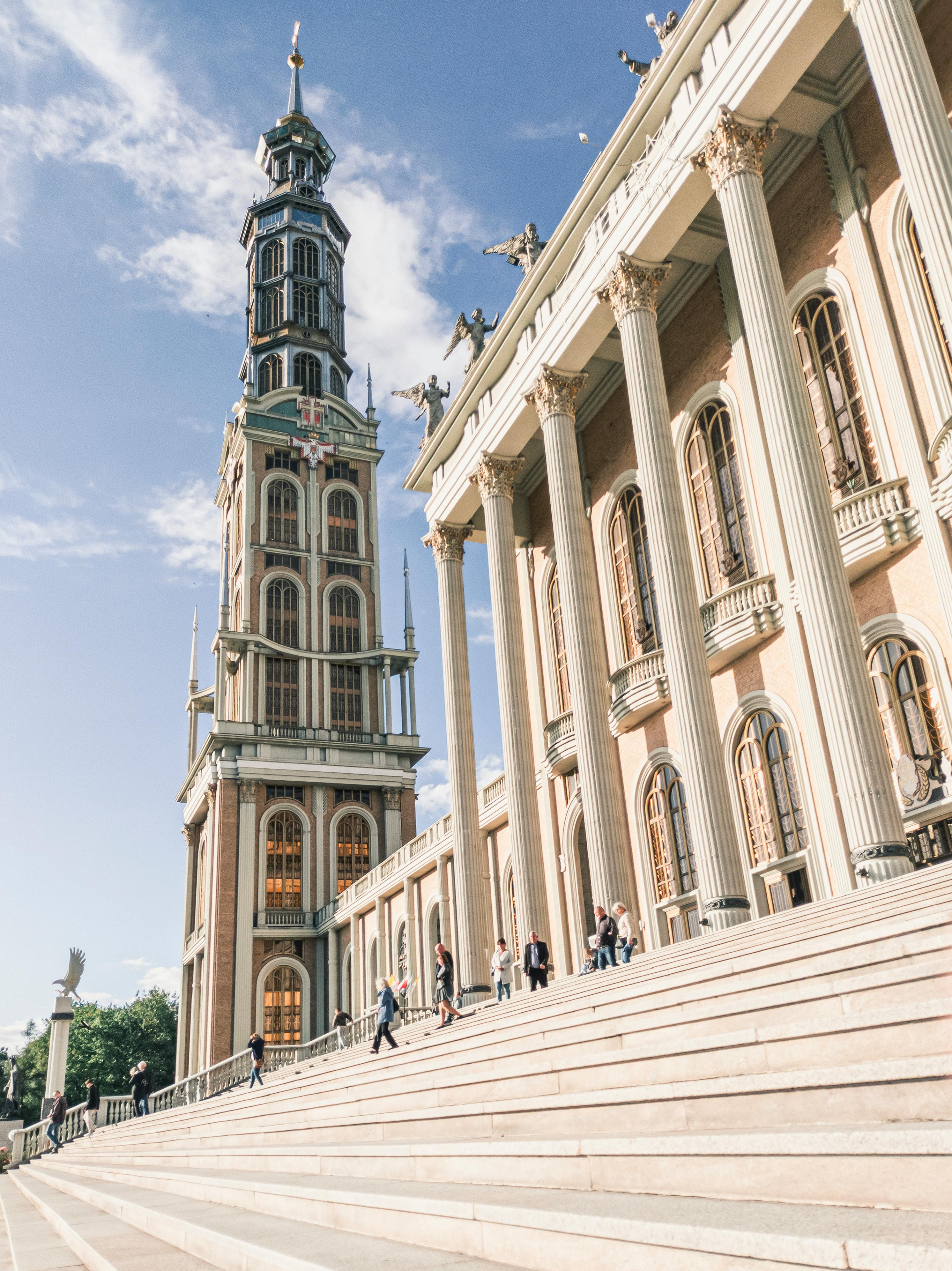 Grand architectural exterior of Licheń Stary Basilica, featuring columns and towering structure under clear sky.