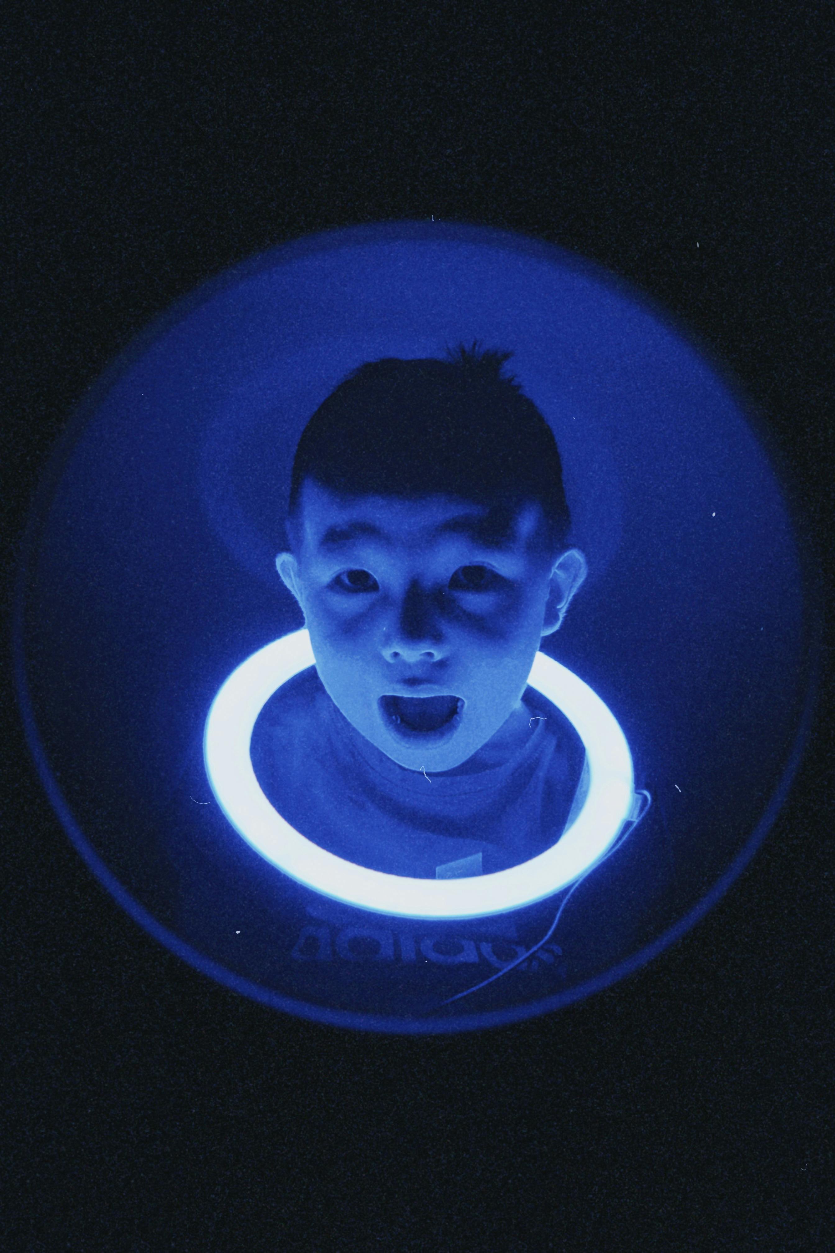 A unique portrait of a child bathed in blue neon light, creating a futuristic vibe.